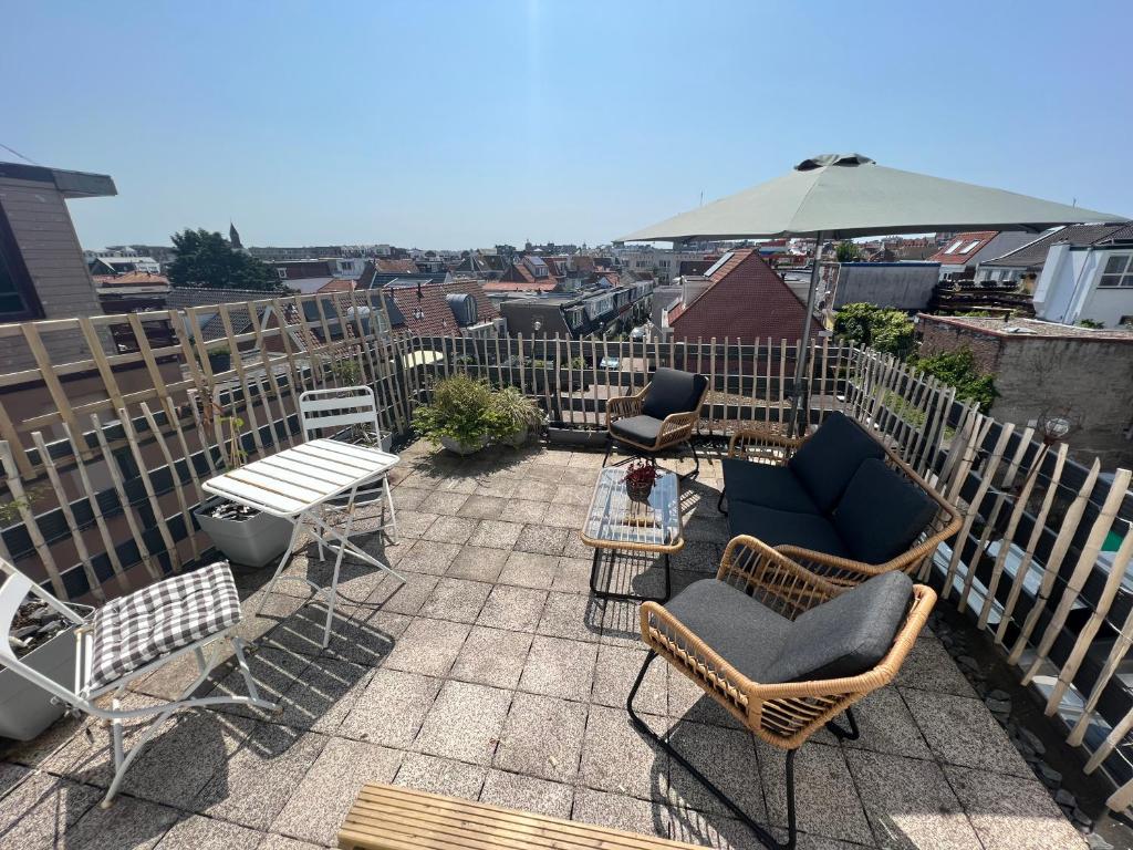 a patio with chairs and tables on a roof at Mel's apartment 2 in Zandvoort