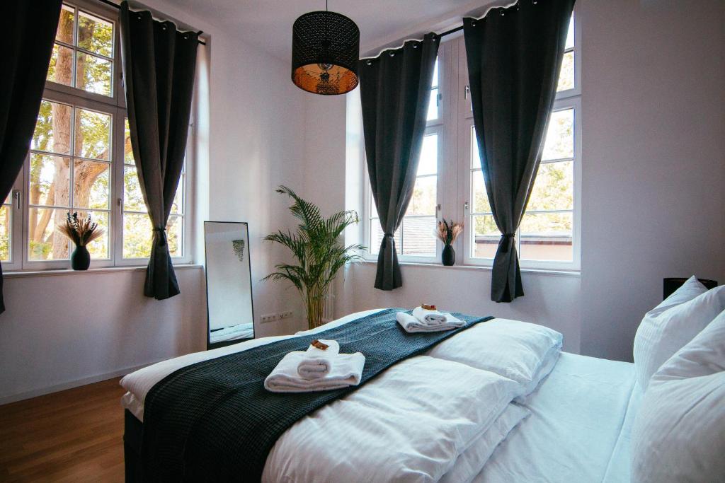 1 dormitorio con 2 toallas en una cama con ventanas en Oasis Appart - Wohnen im Königspark - Elbhang Dresden - große Terrasse - Netflix - TG en Dresden