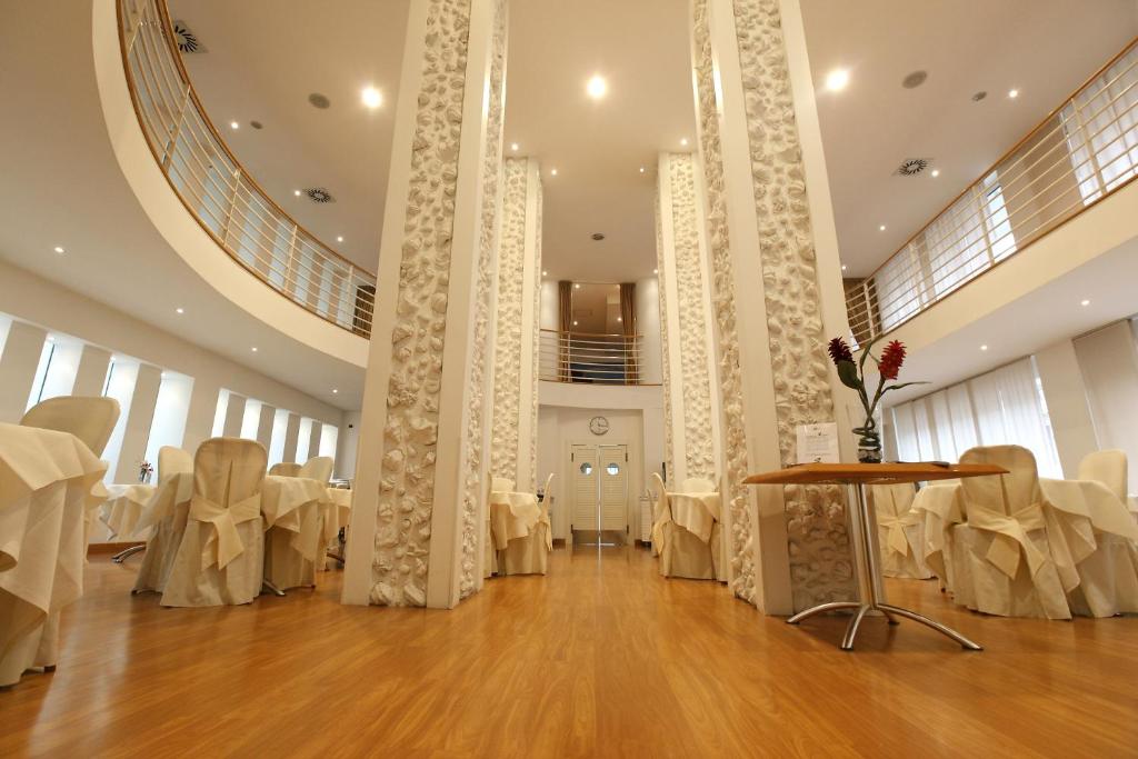 una sala banchetti con tavoli bianchi e sedie bianche di Hotel Luxor a Rimini
