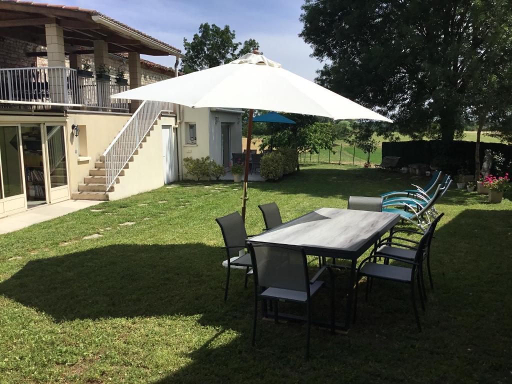 a table and chairs under an umbrella in a yard at Maison de Jade in Noailles