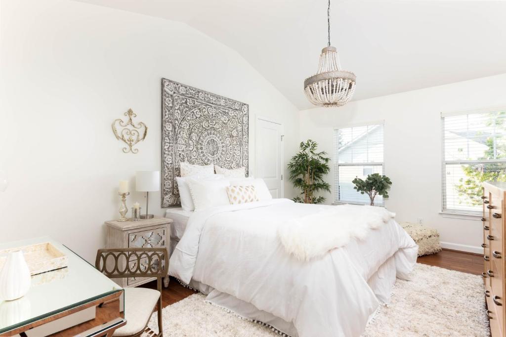 a white bedroom with a large bed and a chandelier at Relax in Style Near the Heart of Music City in Nashville