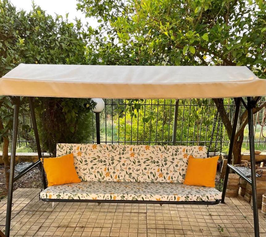 un auvent sur un banc avec deux oreillers orange dans l'établissement SISSOU VILLAGe PLACe, à Kalamata