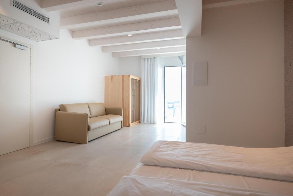 a white room with a bed and a couch at Unico Hotel Caorle in Caorle