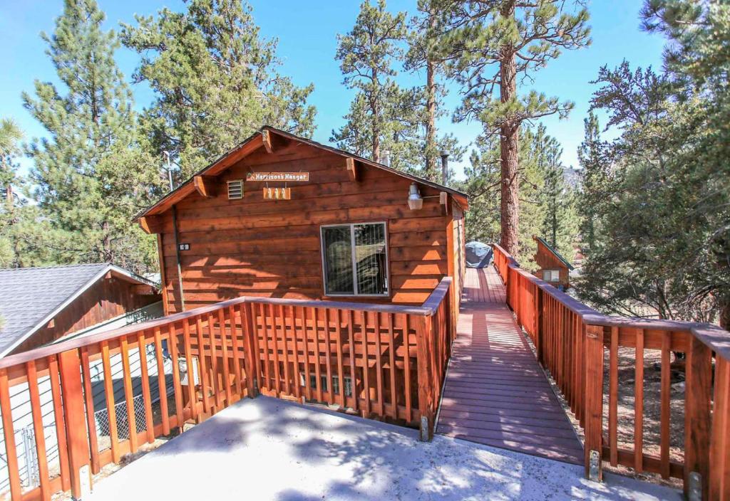a log cabin with a deck and a walkway at Harrison's Hanger - Cozy cabin with a fairly nice view of the tree line! Wood burning fireplace! in Big Bear City
