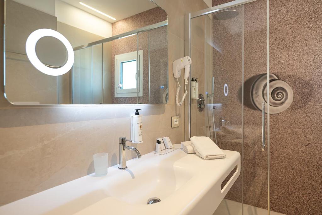 a bathroom with a sink and a mirror and a shower at Unico Hotel Caorle in Caorle