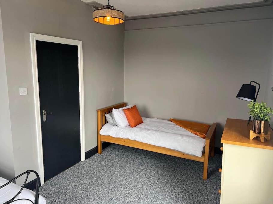 ein Schlafzimmer mit einem Bett mit orangefarbenen Kissen darauf in der Unterkunft Stylish 5 bedroom /7bed apartment in Seacombe