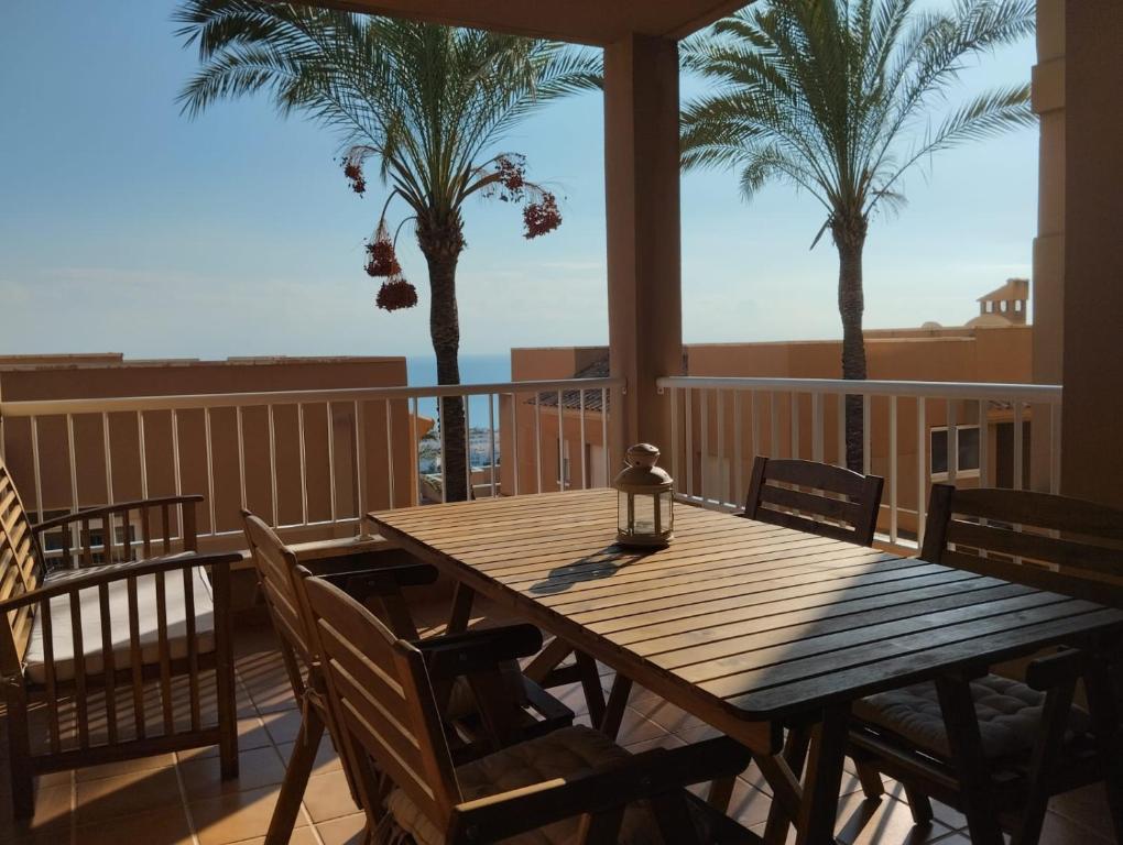 a wooden table and chairs on a balcony with palm trees at Marina Vistamar in Mojácar
