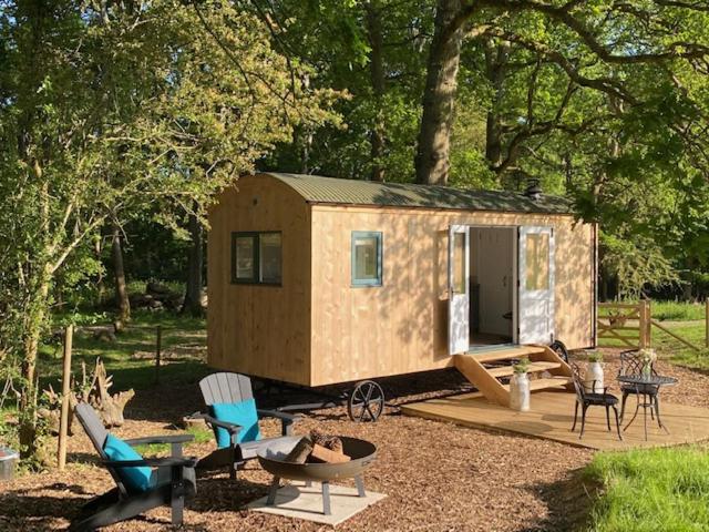 a tiny house in a yard with chairs and tables at Coachroad Shepherds Huts in Petworth
