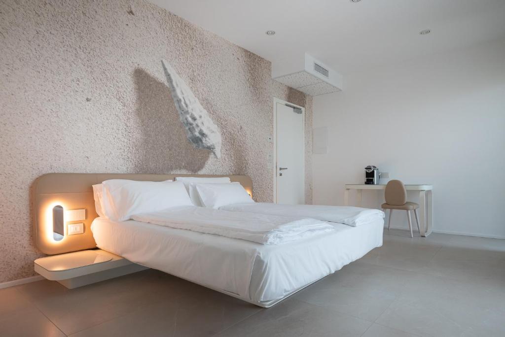 a bedroom with a large white bed and a wall at Unico Hotel Caorle in Caorle