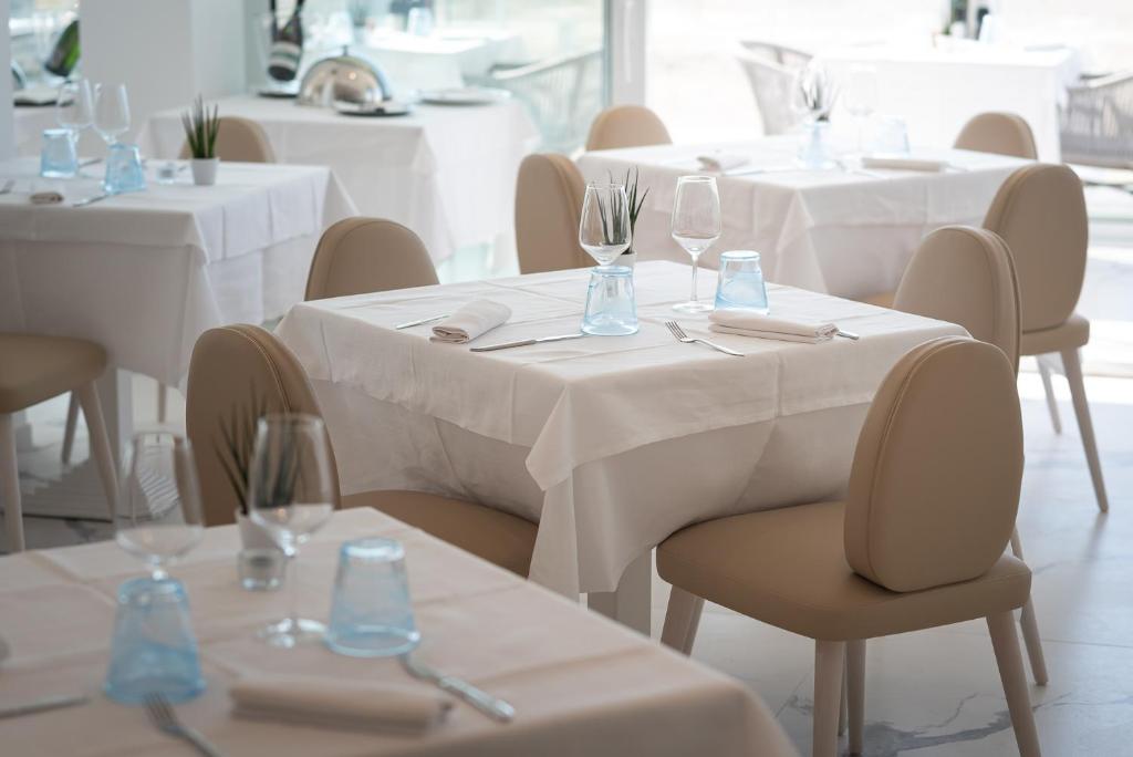 a dining room with tables and chairs with white tablecloths at Unico Hotel Caorle in Caorle