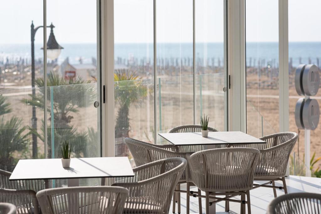 a restaurant with tables and chairs in front of windows at Unico Hotel Caorle in Caorle