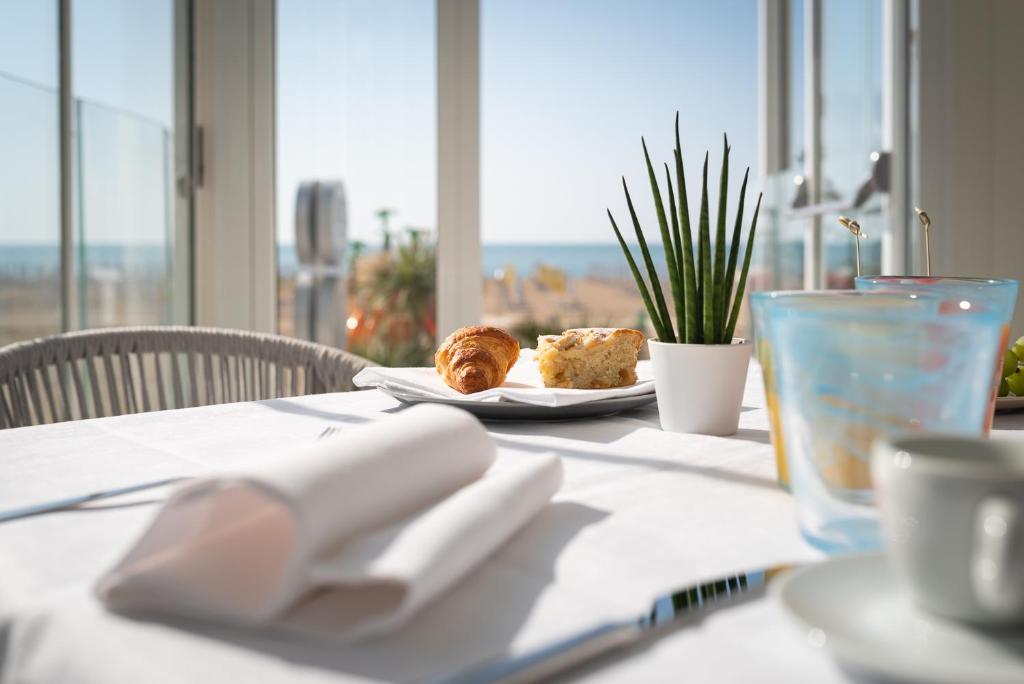 a white table with a plate of food on it at Unico Hotel Caorle in Caorle
