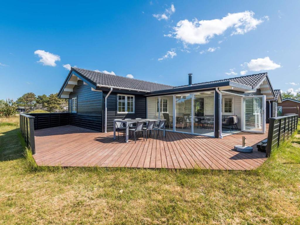 a house with a deck with a table and chairs at Holiday home Fanø CXCVIII in Fanø