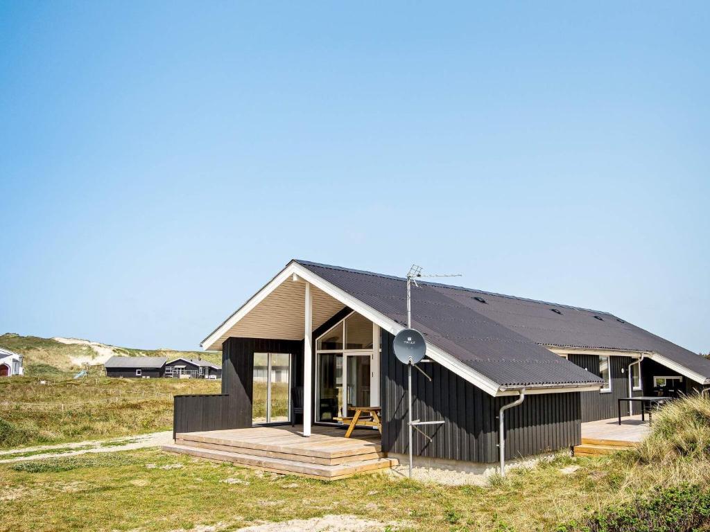 a house with a black roof on a field at Holiday home Harboøre XXIII in Harboør