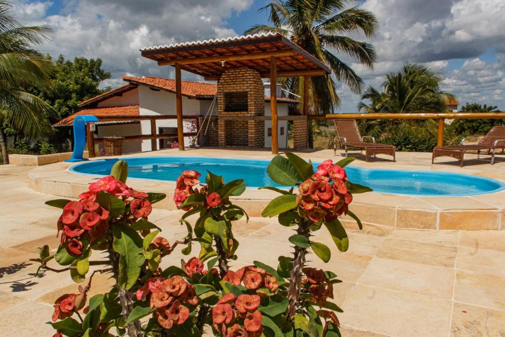 uma piscina com um gazebo e algumas flores em Apartamentos da Jangada em Canoa Quebrada