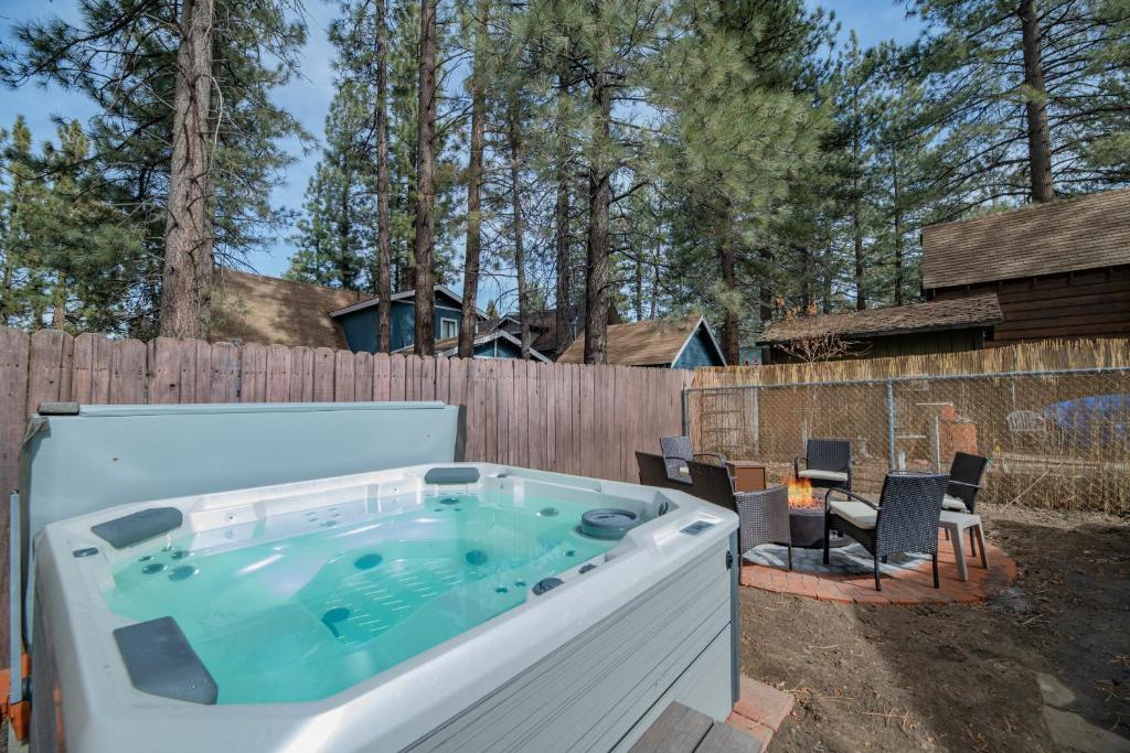 una bañera de hidromasaje en un patio trasero con una valla en Sherwood Cottage - Charming and cozy cabin that has back deck with a Hot Tub!, en Big Bear City