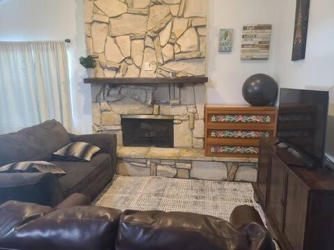 a living room with a couch and a stone fireplace at GCRetreat in Upland