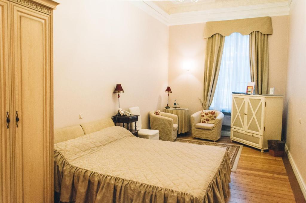 a bedroom with a bed and a chair and a window at Casa Leto in Saint Petersburg
