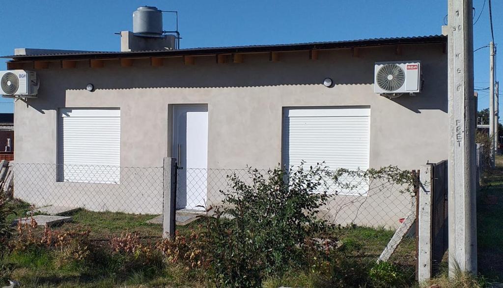 a building with three doors and a fence at Posada Atardeceres in Puan