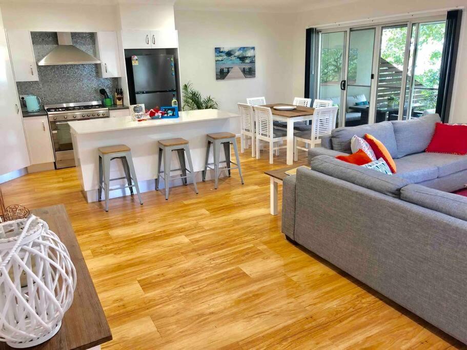 a living room with a couch and a kitchen at DELUXE Escape! Central, NEW & Spacious 3 Bed in Yamba