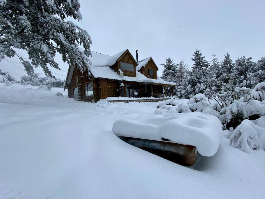 una cabaña de madera cubierta de nieve frente a una casa en Lyford's Boutique Retreat - Relax & Enjoy, en Mt Lyford