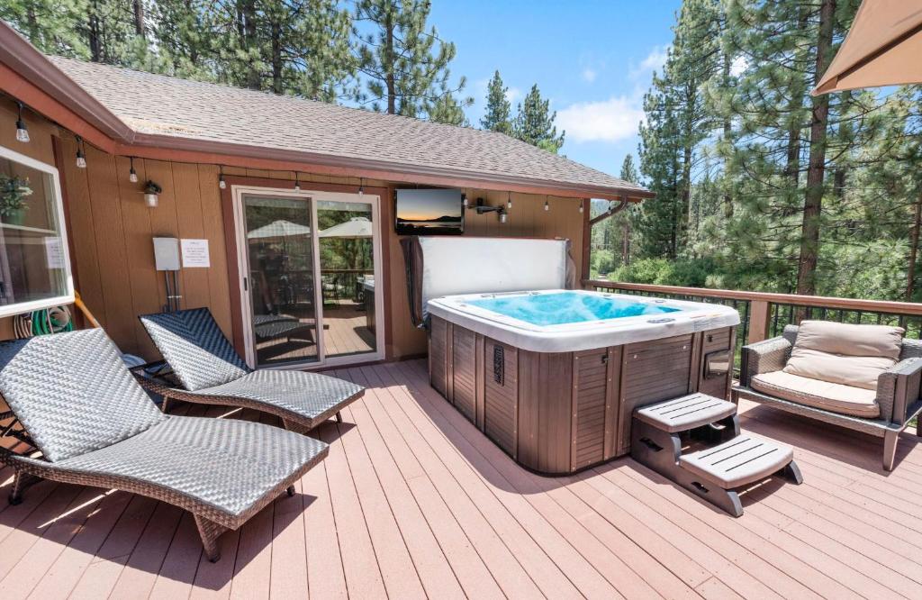 a hot tub on a wooden deck with two chairs at Paradise Peak - One of kind and breathtaking log cabin with Hot Tub and Game Room! in Big Bear Lake