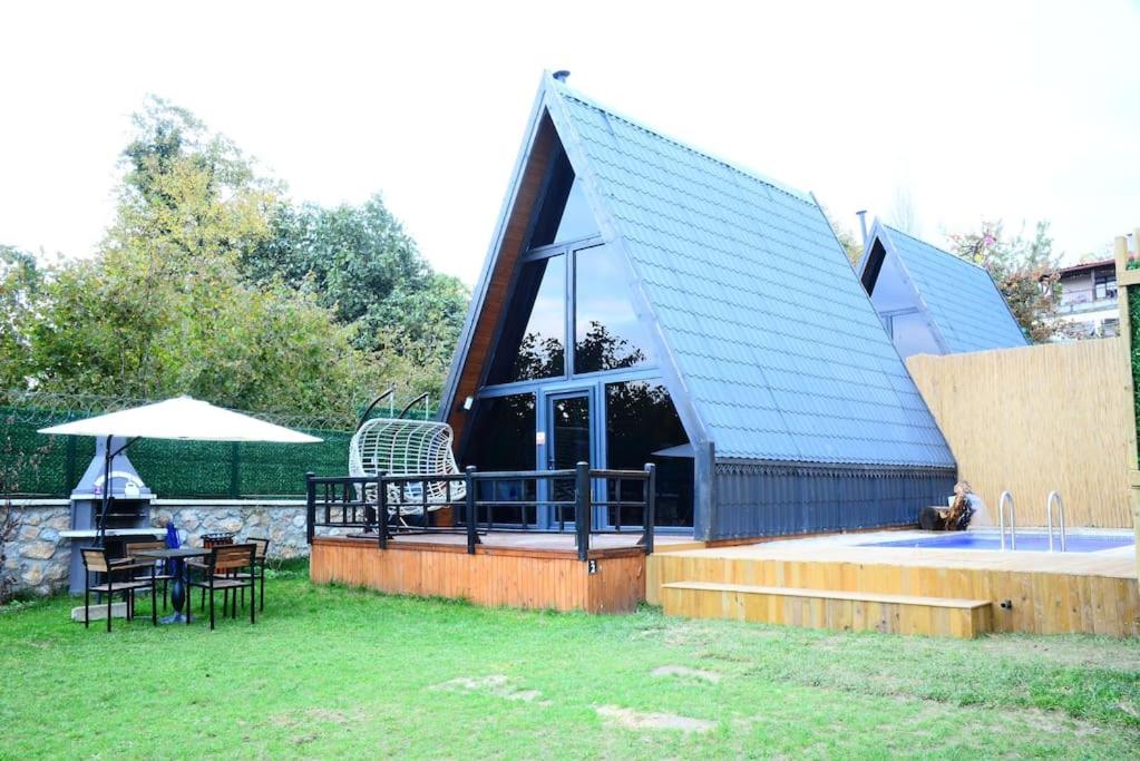 ein Haus mit einem blauen Dach mit einem Tisch und Stühlen in der Unterkunft VİLLA BUNGALOW in Kartepe