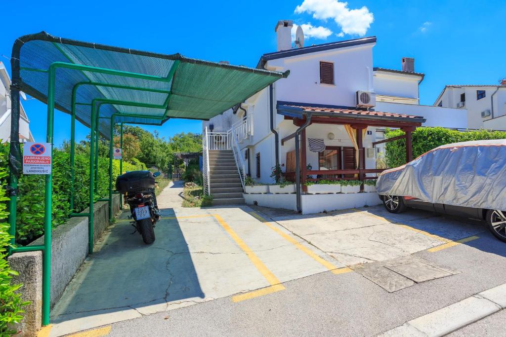 ein Motorrad auf einem Parkplatz neben einem Haus geparkt in der Unterkunft Apartments with a parking space Njivice, Krk - 20542 in Njivice