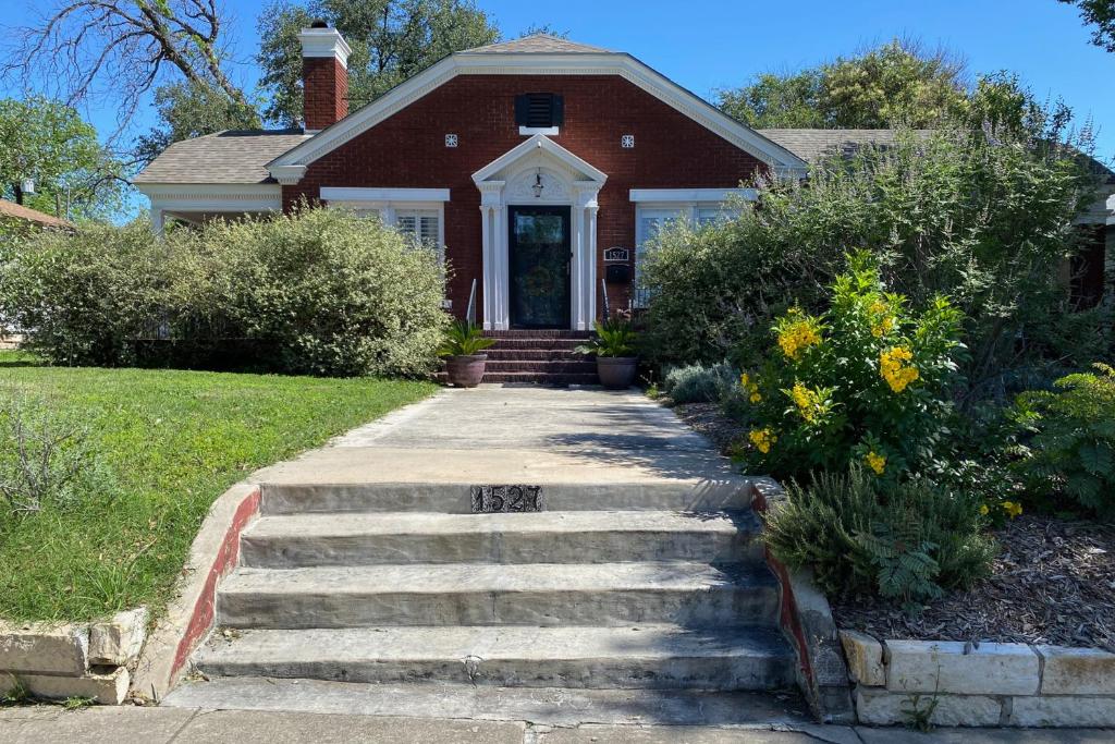 a red brick house with stairs leading to the front door at Woodlawn Avenue Beauty in San Antonio