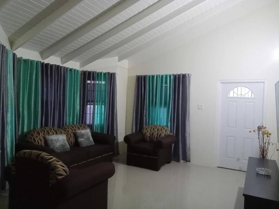 uma sala de estar com duas cadeiras e cortinas verdes em Ital Vibes Get Away em Falmouth