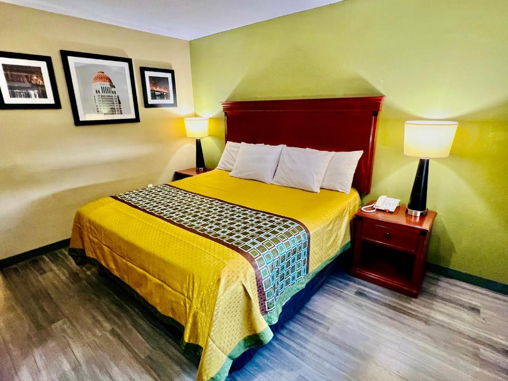 Habitación de hotel con cama con colcha amarilla en Deluxe Inn Miami OK, en Miami
