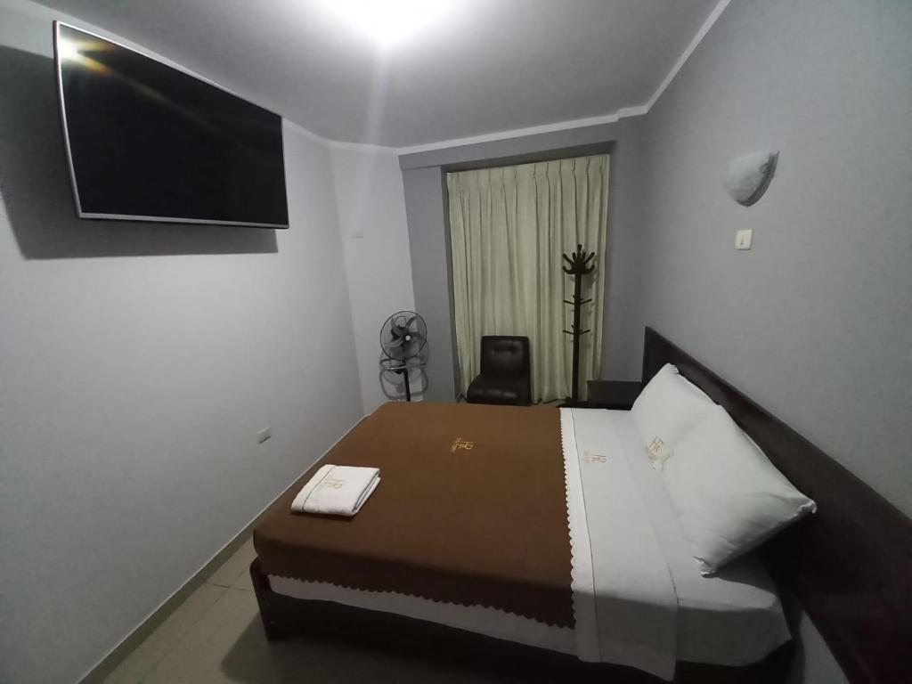 HOSTAL ROGGERIO SRL في بارانكا: غرفة نوم مع سرير وتلفزيون على الحائط