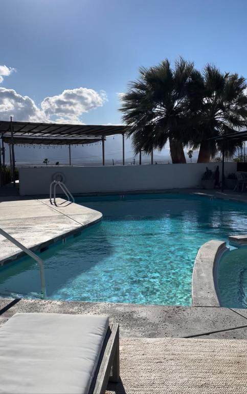 a swimming pool with blue water and palm trees at Miracle Manor Boutique Hotel & Spa in Desert Hot Springs