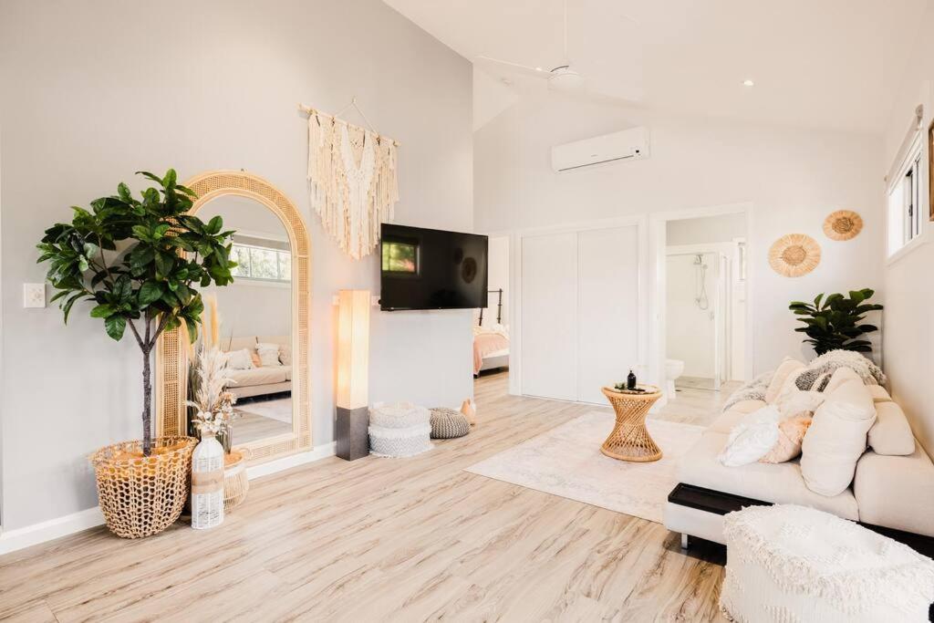 a white living room with a couch and a mirror at An Idyllic Boho Style Retreat High-end kitchenware in Gold Coast