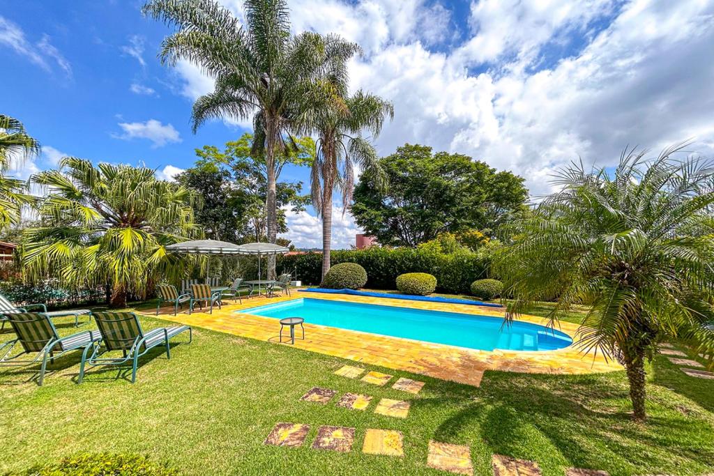 einen Pool in einem Garten mit Stühlen und Palmen in der Unterkunft Casa com WiFi e otima localizacao em Sao Roque SP in São Roque
