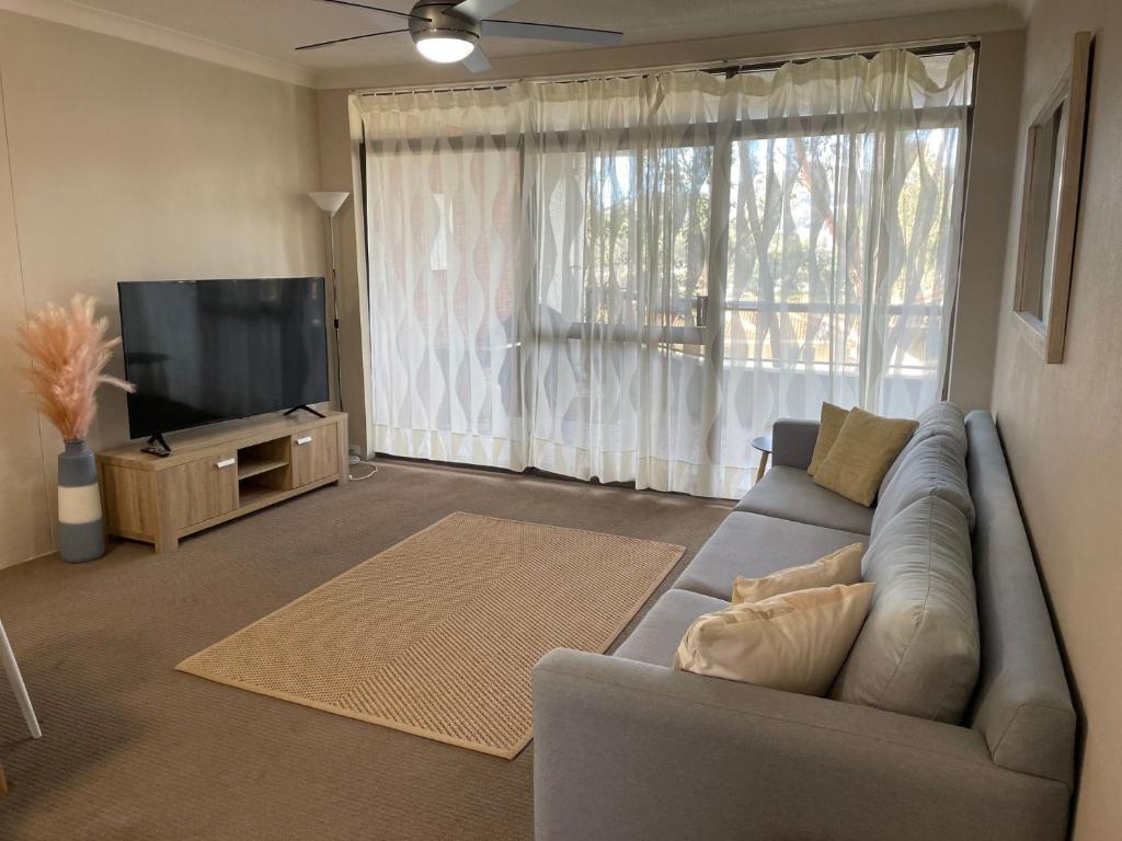 a living room with a couch and a flat screen tv at The Commodore, 14, 9-11 Donald Street- Unit in the heart of town with views & free wi-fi in Nelson Bay