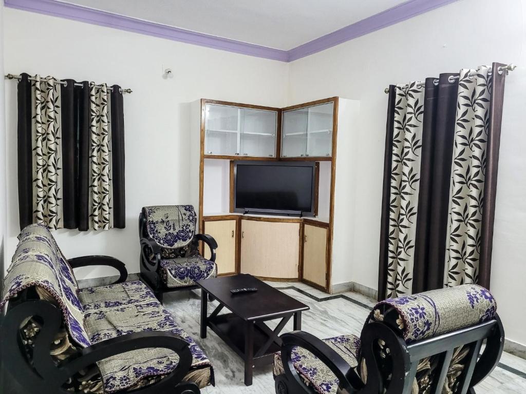 uma sala de estar com cadeiras e uma televisão de ecrã plano em KORA'S HOME STAY em Tirupati