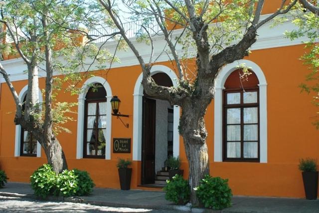 un edificio naranja con dos árboles delante de él en Hotel La Mision, en Colonia del Sacramento