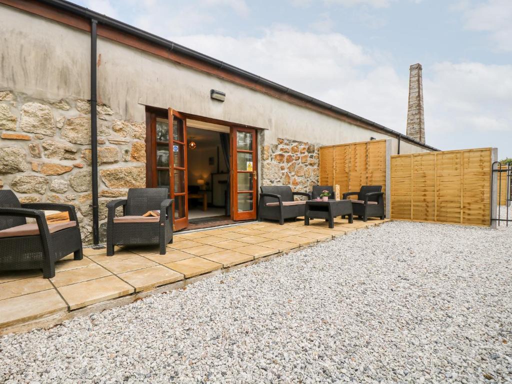 a patio with chairs and a stone building at The LinneyThe West Dry in St Austell