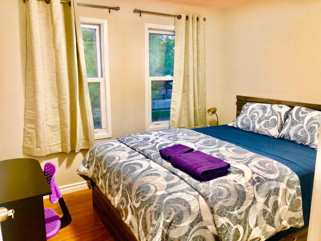 um quarto com uma cama com lençóis roxos e janelas em CozyHome em Markham