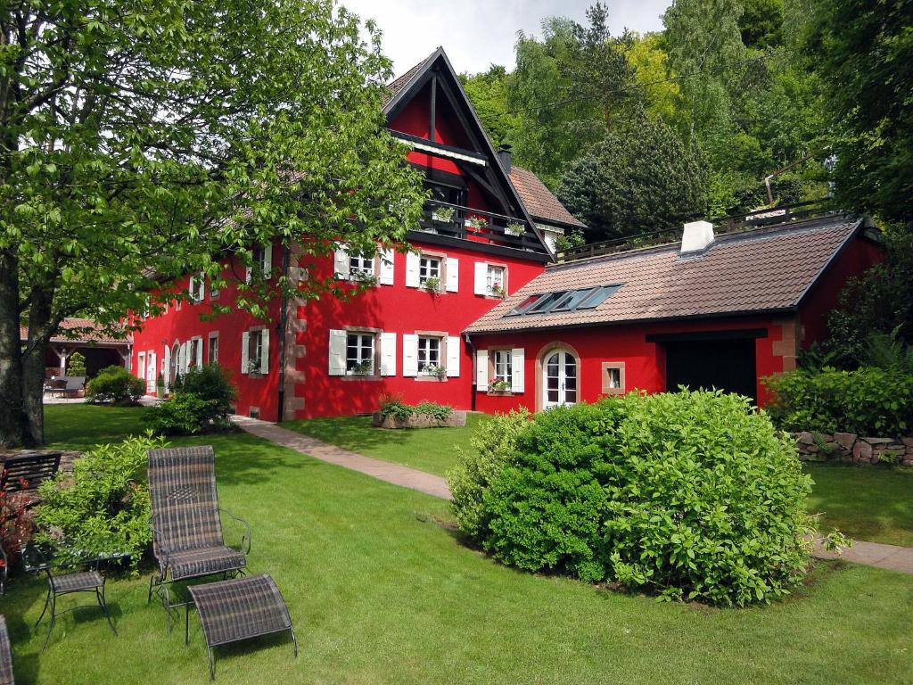 una casa roja con sillas delante en La Haute Grange Gîtes de Charme en Alsace, en Fréland