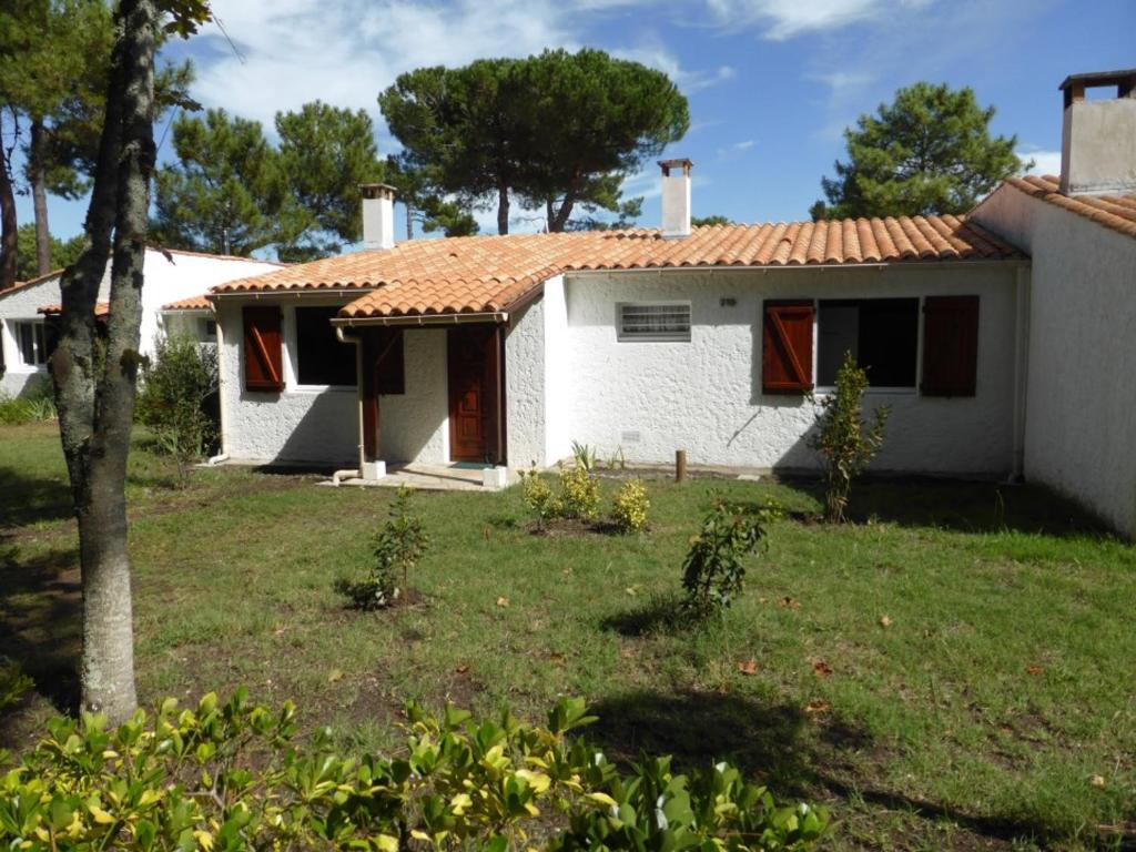 une petite maison blanche avec une cour gazonnée dans l'établissement Maison 3 pièces à La Palmyre, proche mer, patio et parking, 4 pers. - FR-1-705-47, aux Mathes