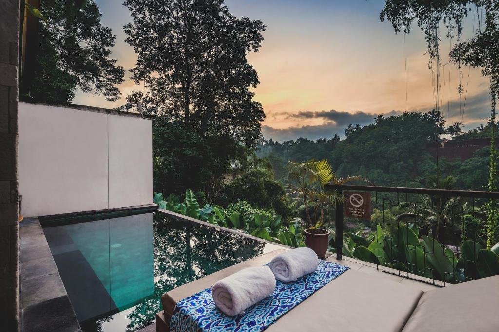 a room with a balcony with towels on a table at Amora Ubud Boutique Villas in Ubud