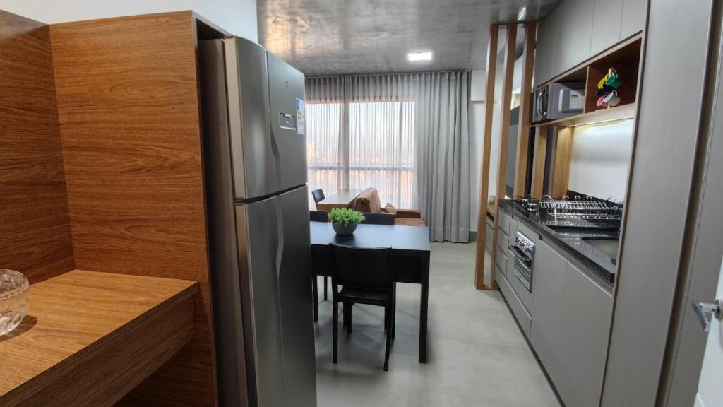 una cucina con frigorifero in acciaio inossidabile e tavolo di ID Vida Urbana Setor Oeste Goiânia 3703A a Goiânia