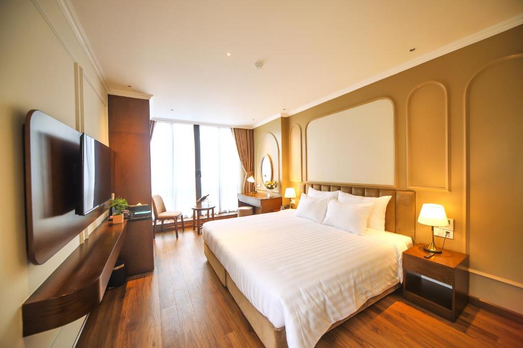 L'amant de Hanoi Hotel - khách sạn Lamant de Hà Nội في هانوي: غرفة فندقية بسرير وتلفزيون بشاشة مسطحة