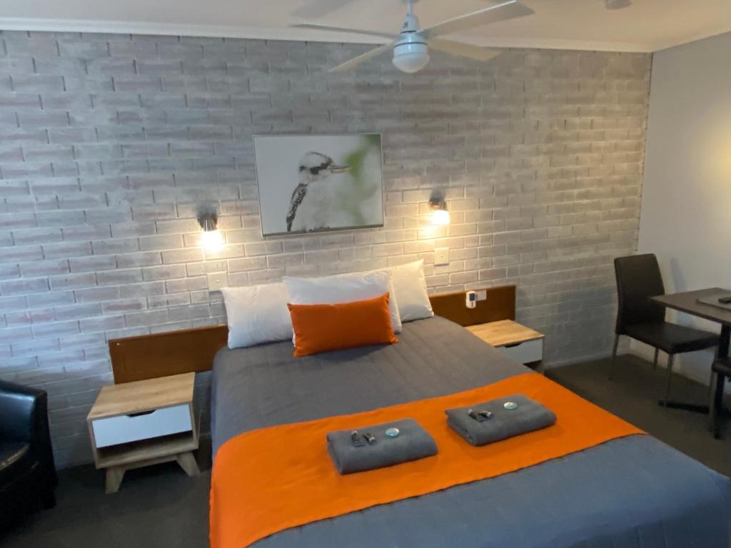 a bedroom with a large bed with an orange blanket at Creswick Motel in Creswick