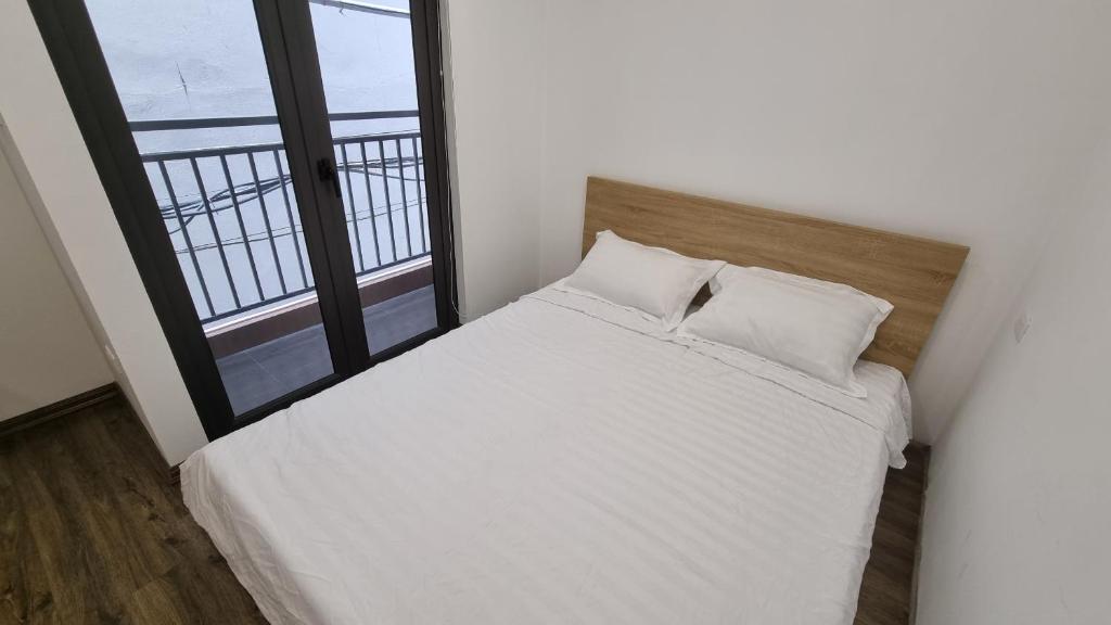 a bedroom with a white bed and a large window at Era Apartment Khuc Thua Du in Hanoi