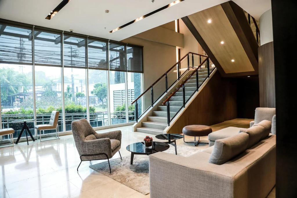 eine Lobby mit einer Treppe, einem Sofa und Stühlen in der Unterkunft Sotogrande Hotel Katipunan in Manila