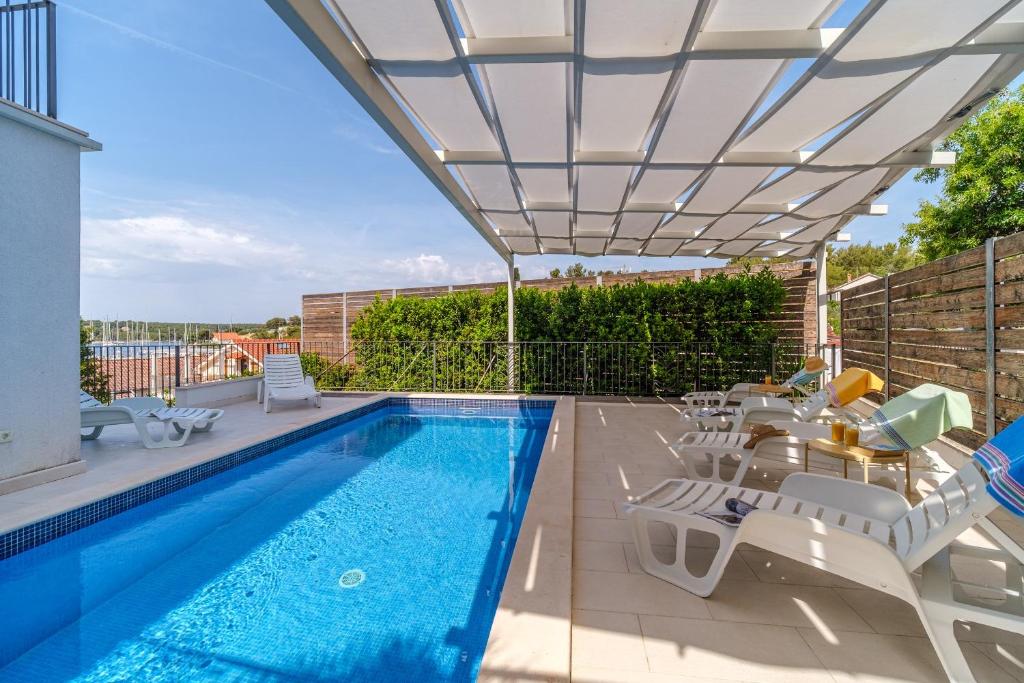 Holiday home Mila - private pool في ميلنا: فناء مع مسبح وكراسي ومظلة فناء