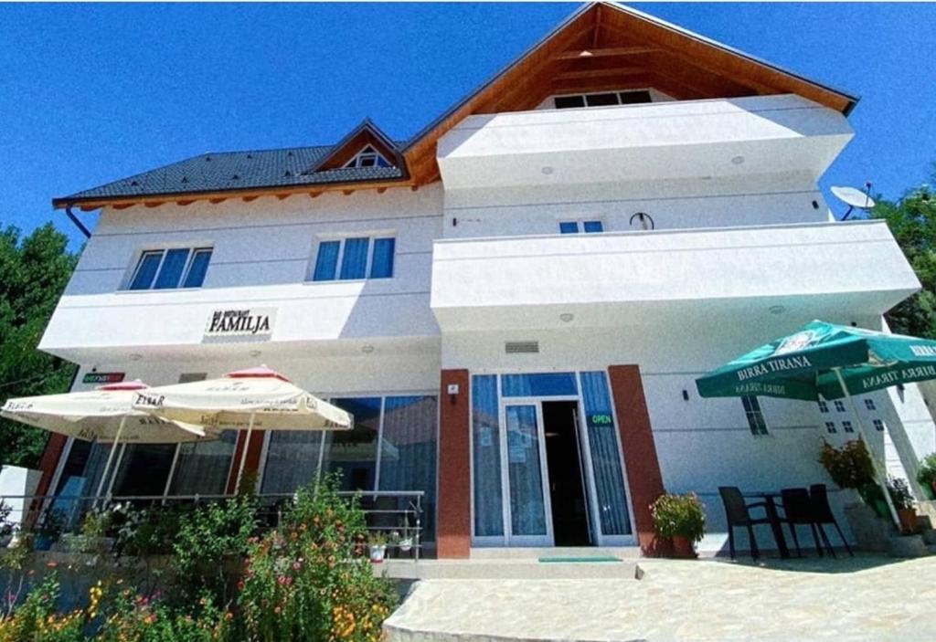ein Gebäude mit zwei Sonnenschirmen davor in der Unterkunft Bar-Restaurant-Hotel-Familja in Klos
